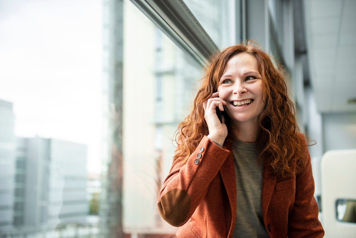 A smiling woman talks on her smartphone.