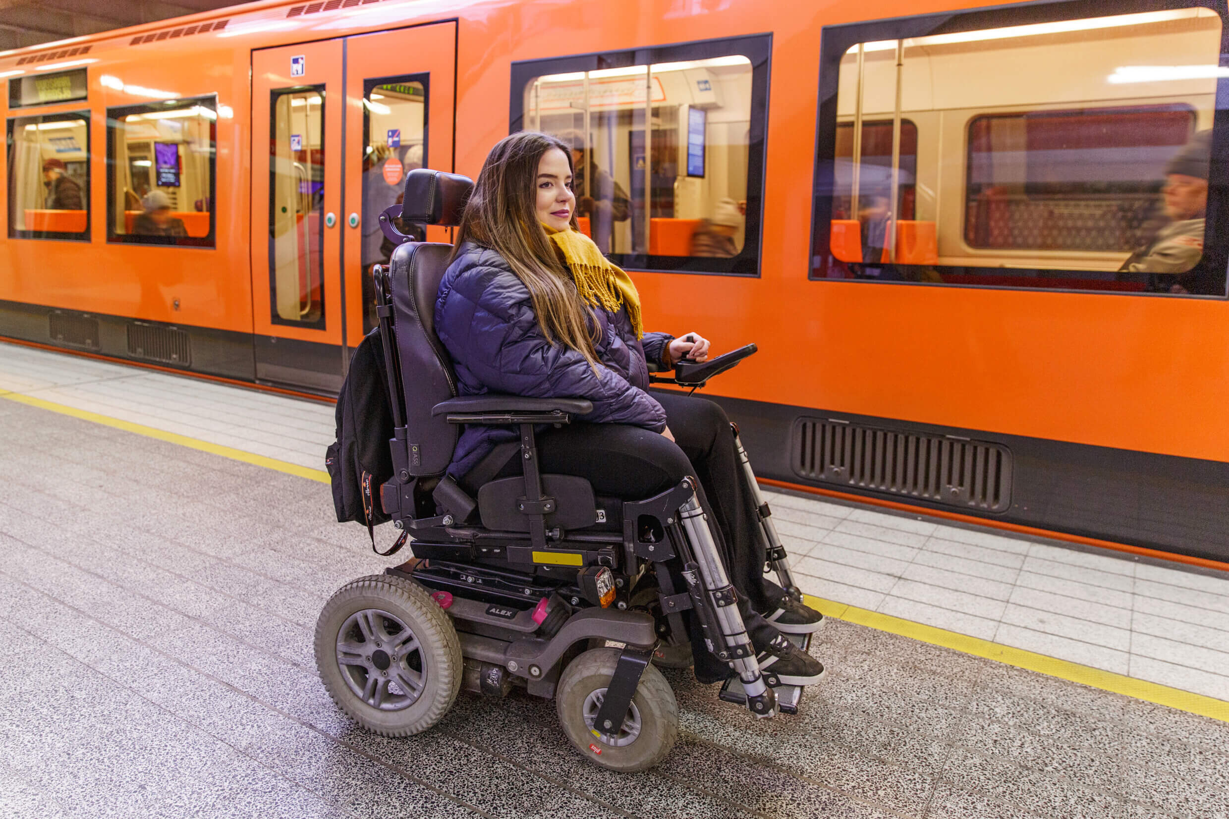 Woman waits for a metro sitting in a electric wheelchair.