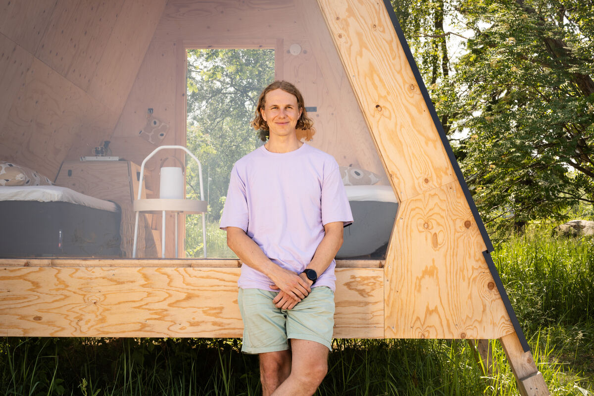 A person smiles at the camera outside of a tent.