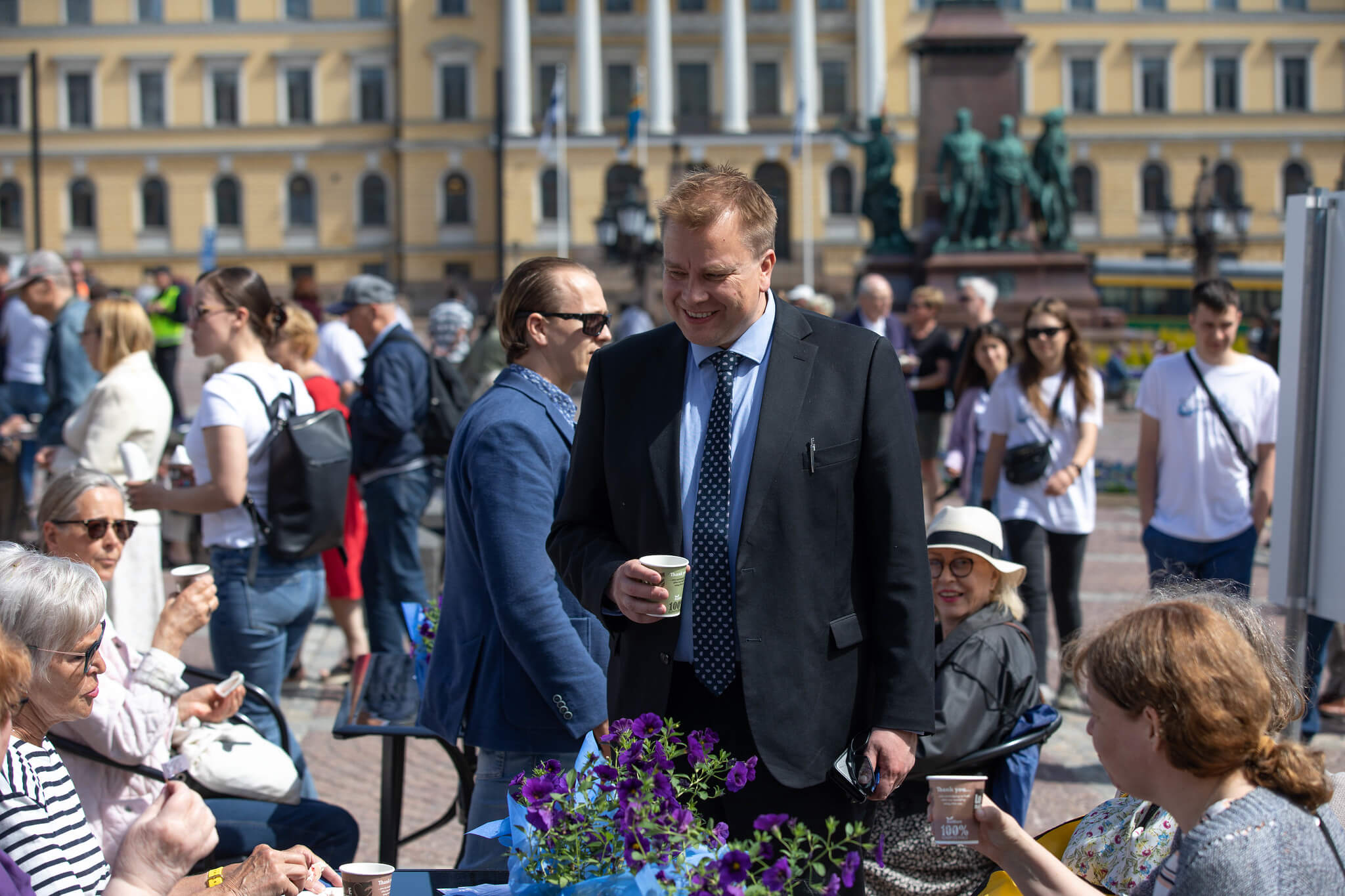 The Finnish Minister of Defence drinks coffee in a city square.