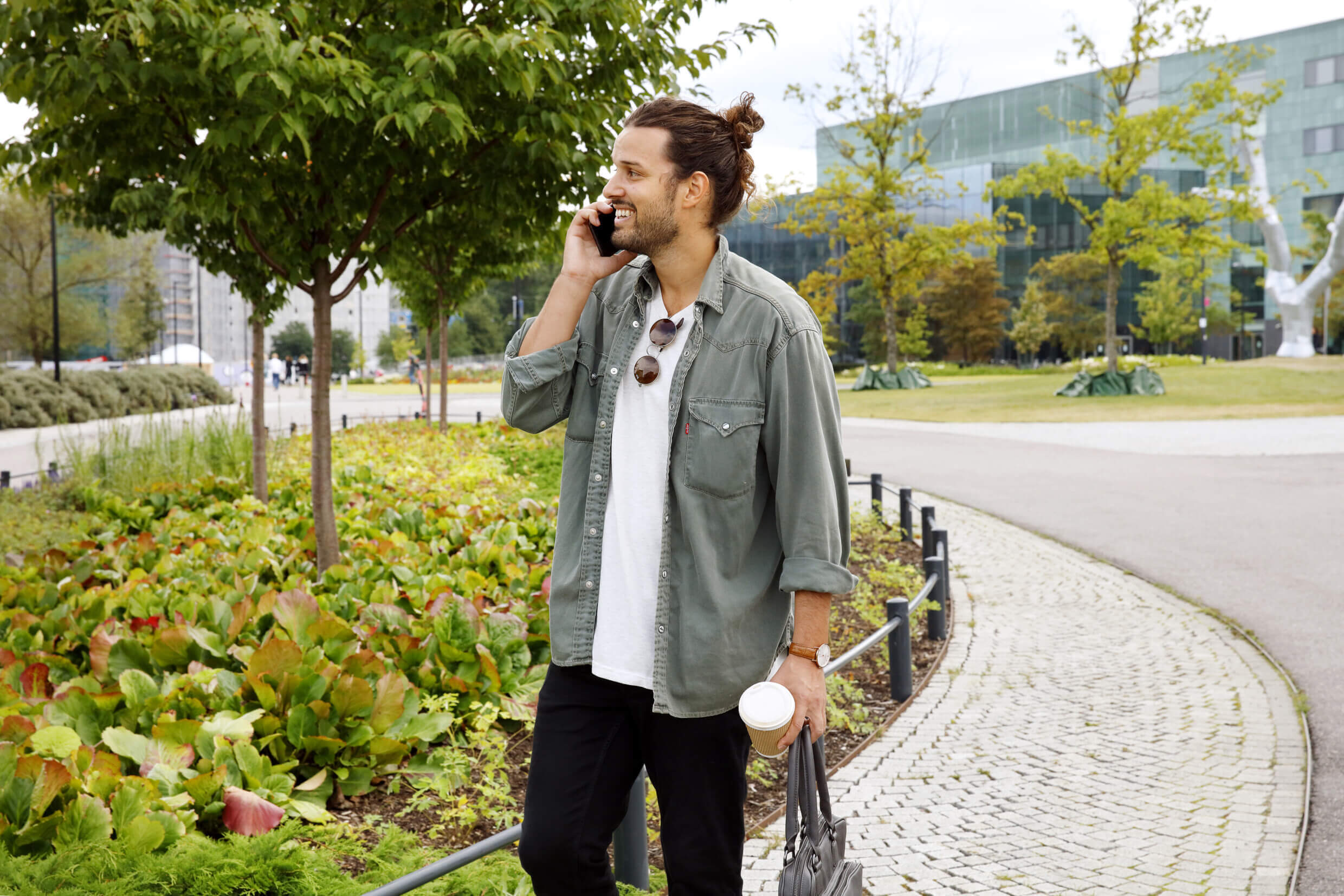 A man talks on the phone outside of an office complex.